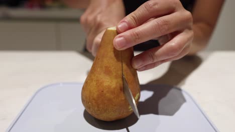 person slicing a pear on a cutting board