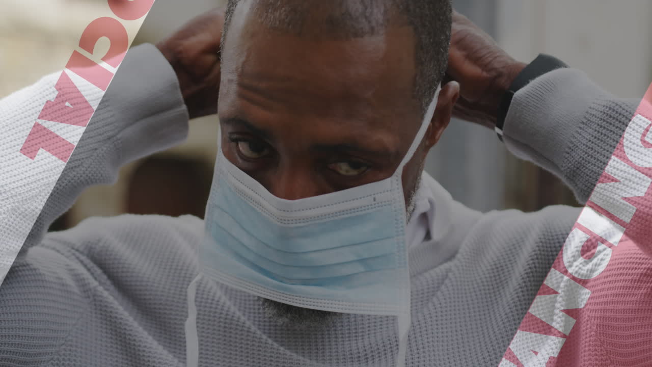 Animation of covid 19 social distancing text over african american man putting face mask on