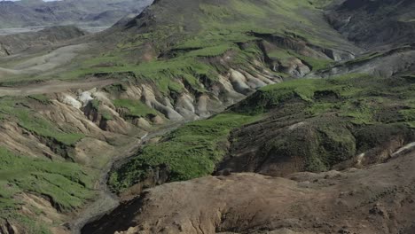 green grass covers slopes of old geothermal valley in iceland, aerial