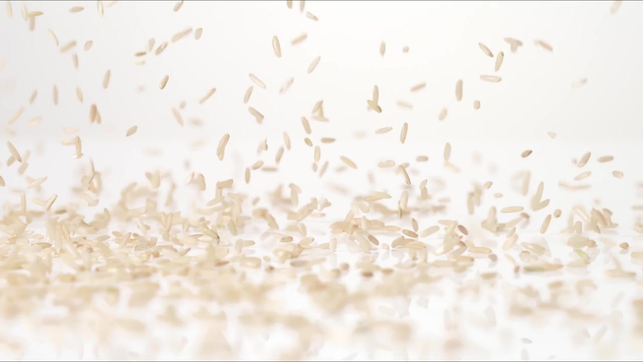 Riso integrale secco non cotto che rimbalza su un tavolo bianco in slow motion, in primo piano macro, prima di depositarsi