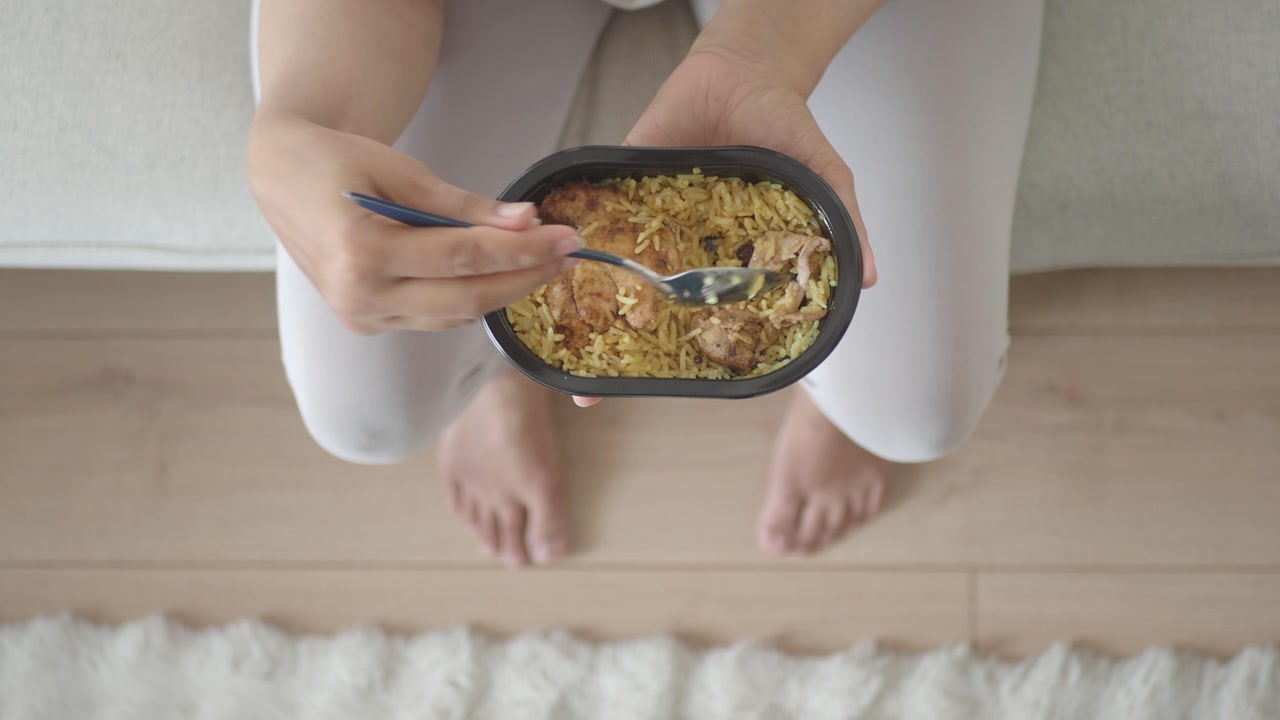 Overhead View of Person Eating a Prepared Rice and Chicken Meal