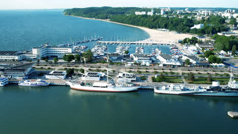 aerial view of parking boats and ships at harbor of gdynia with marina and coastline during sunny day