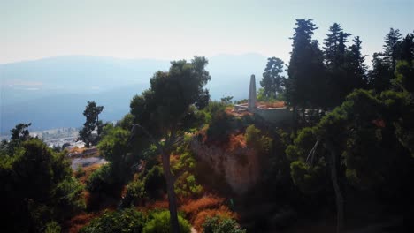 stone monument on a hill amidst trees with mountainous landscape