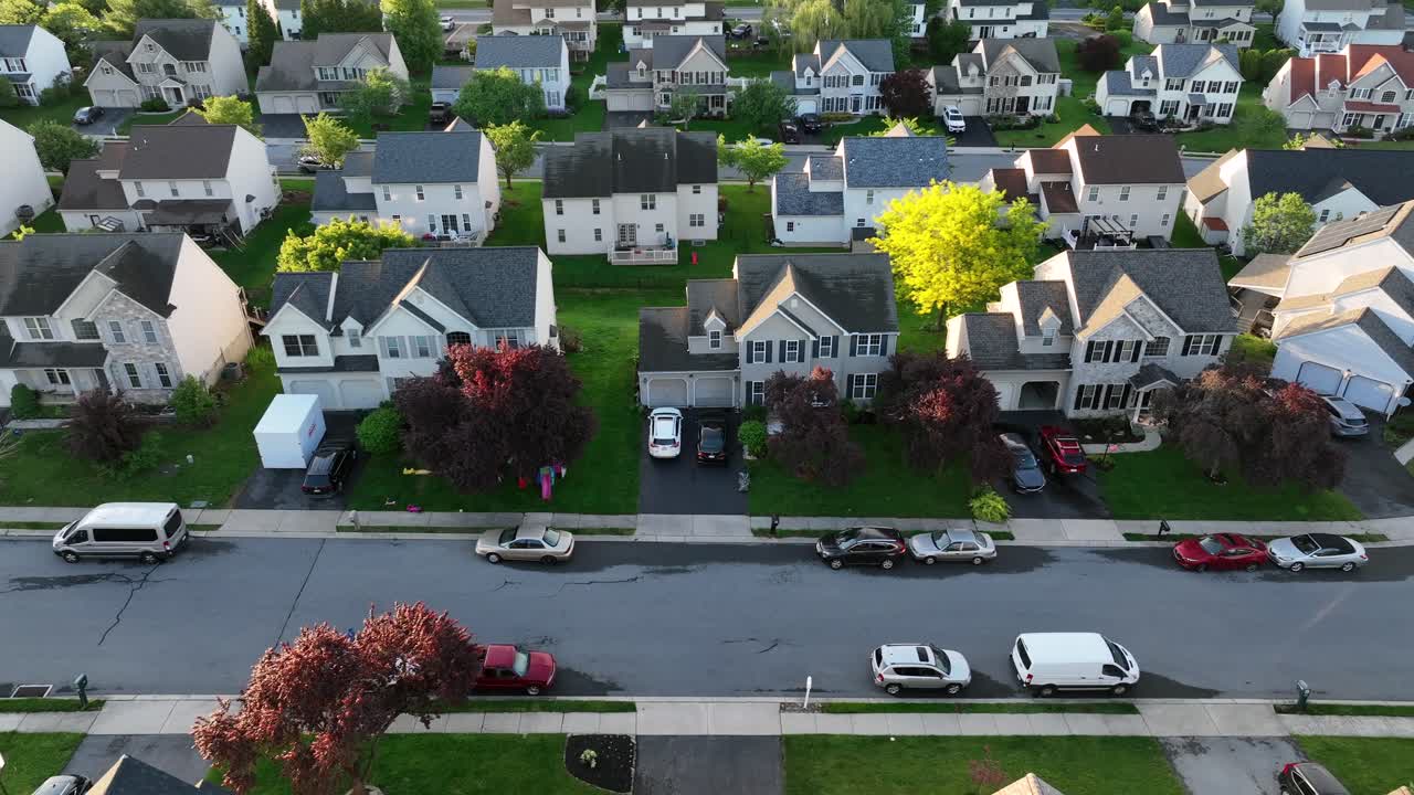 American suburb neighborhood at sunrise in spring. Aerial drone shot of single family houses with parking cars. New modern neighborhood in suburbia.Aerial lateral wide shot scene .USA retirement homes