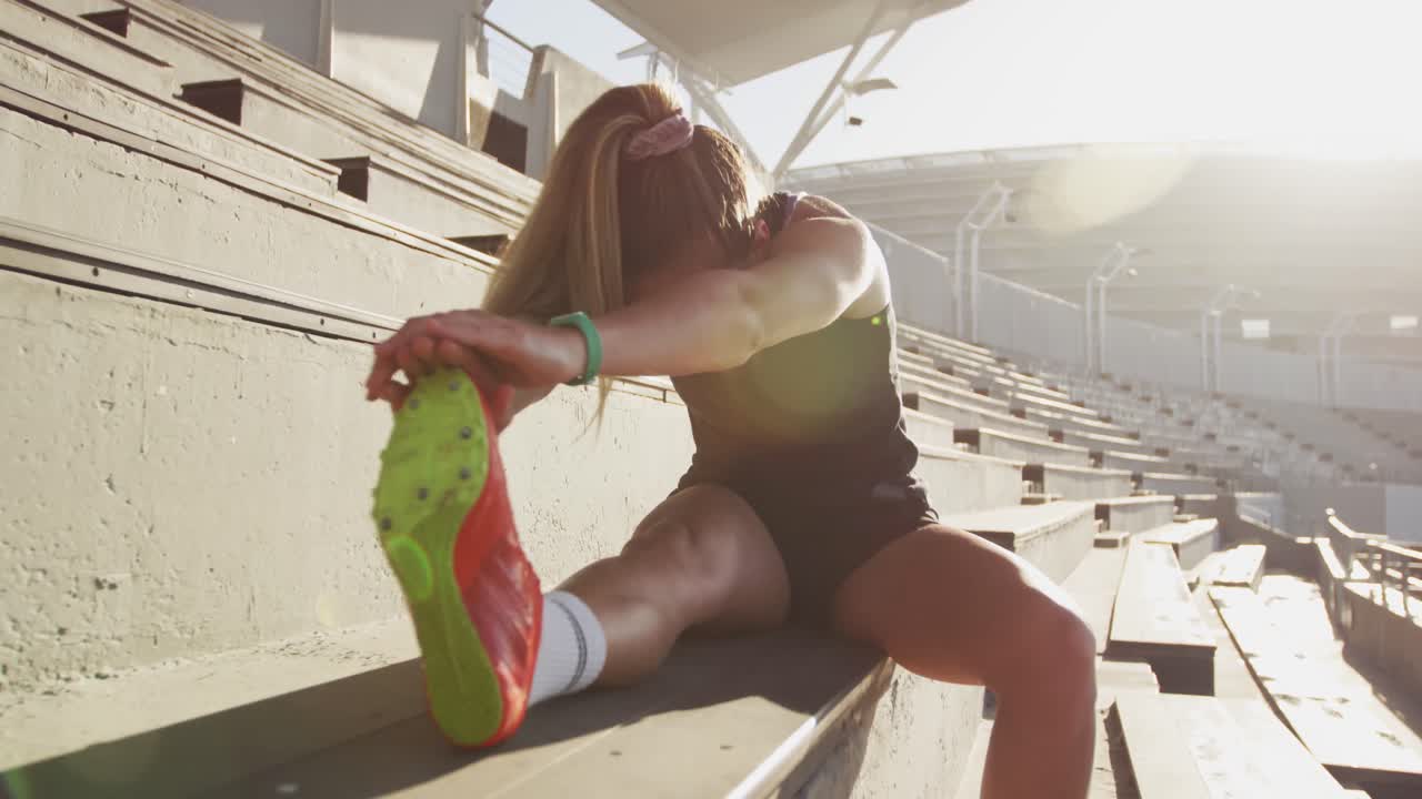 atleta caucásico estirándose en el estadio