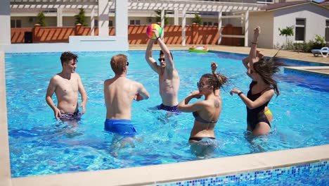 group of young friends playing volley ball in the swimming pool