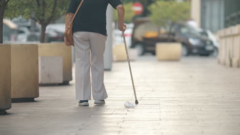 elderly woman with stick walking in the street