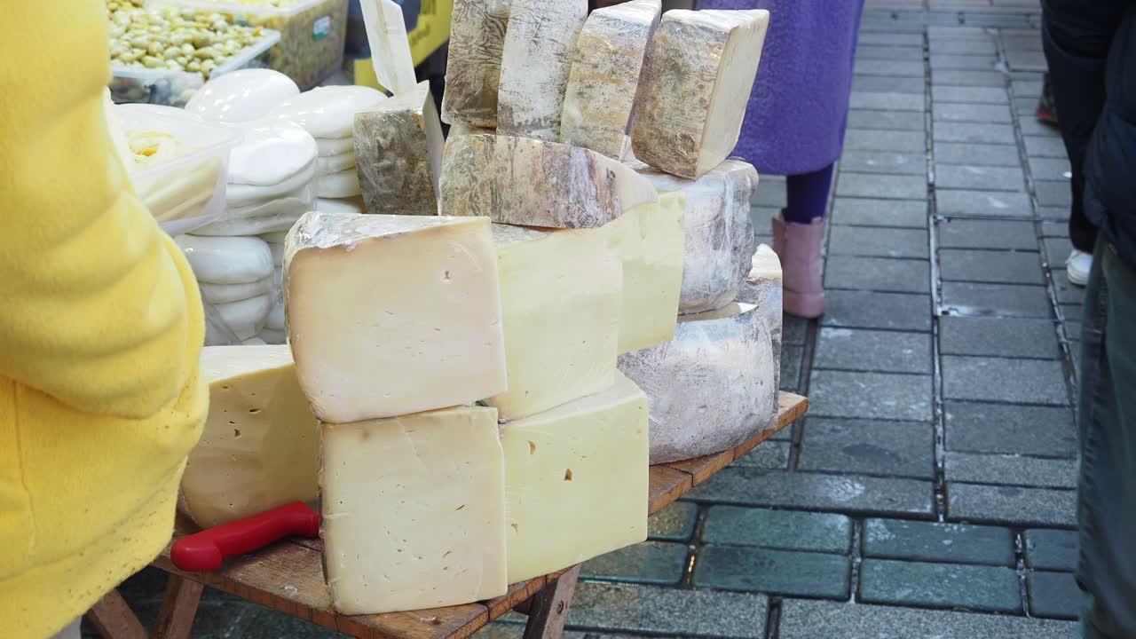 un vendedor que vende diferentes tipos de queso en un mercado callejero
