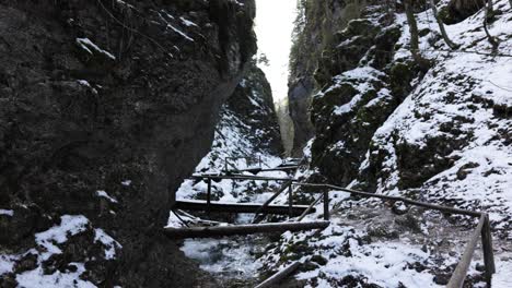 puente de madera entre escarpados acantilados cubiertos de nieve durante el invierno