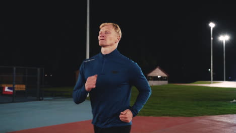 focused blond man running in the park at night 2