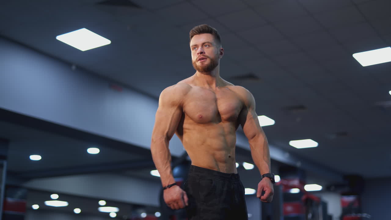 Young bodybuilder weightlifter with an ideal body. Handsome sportsman without shirt showing his abdominal muscles, biceps and triceps.