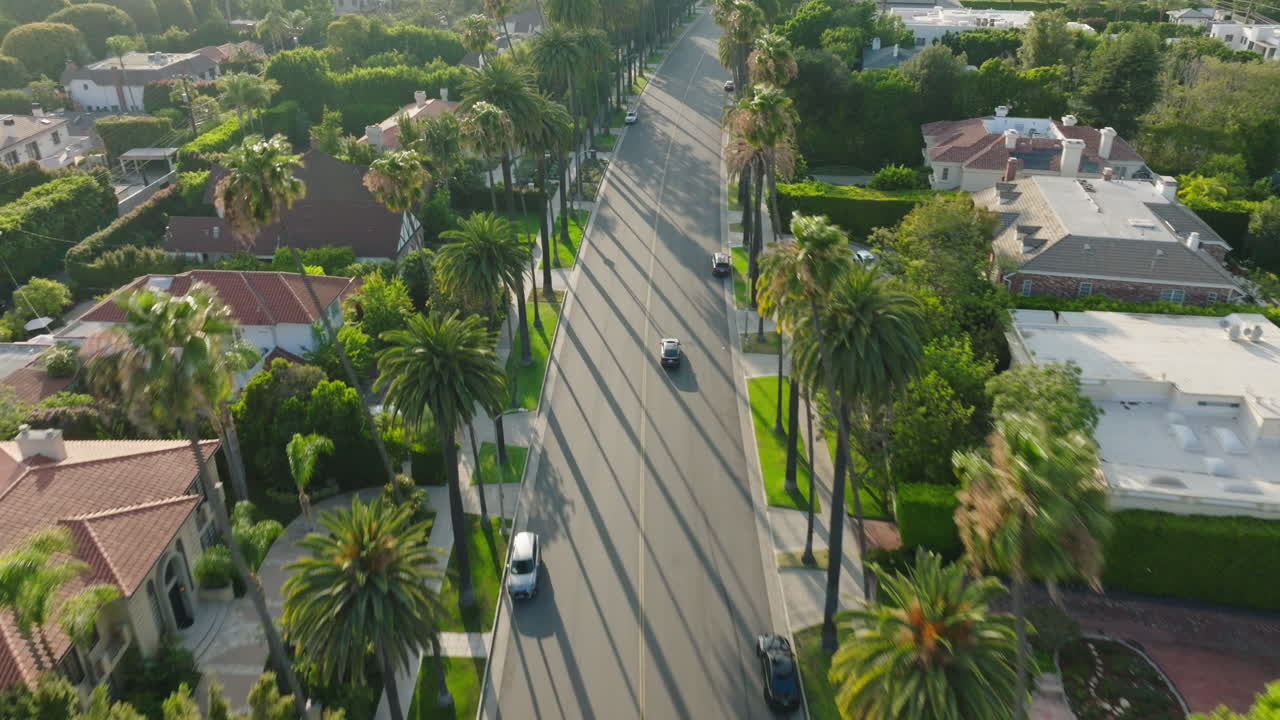 Volo sopra una strada a Beverly Hills, ripresa aerea con drone di un'auto che percorre una strada pittoresca in un soleggiato pomeriggio californiano
