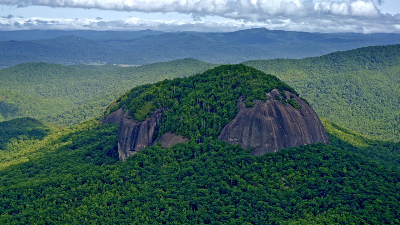 drone shot of large monolith or lone mountain in the middle of forested valley