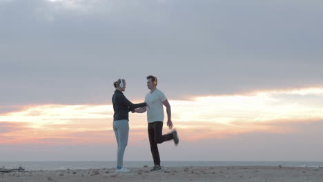 Young-people-in-headphones-exercising-on-the-beach