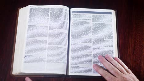 Top-down-shot-of-a-leather-bound-bible-being-opened-up-to-the-book-of-Mark