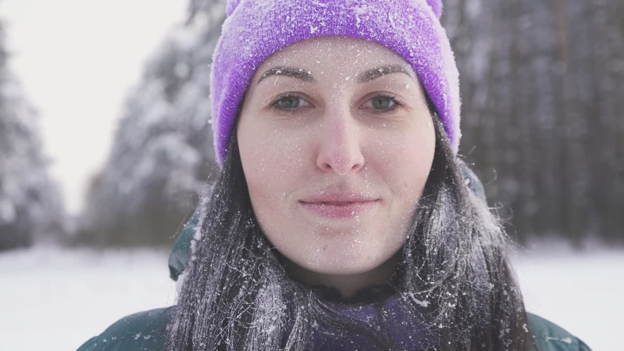 lonely girl in the woods smiling looking at the camera, covered with snow after a snow storm
