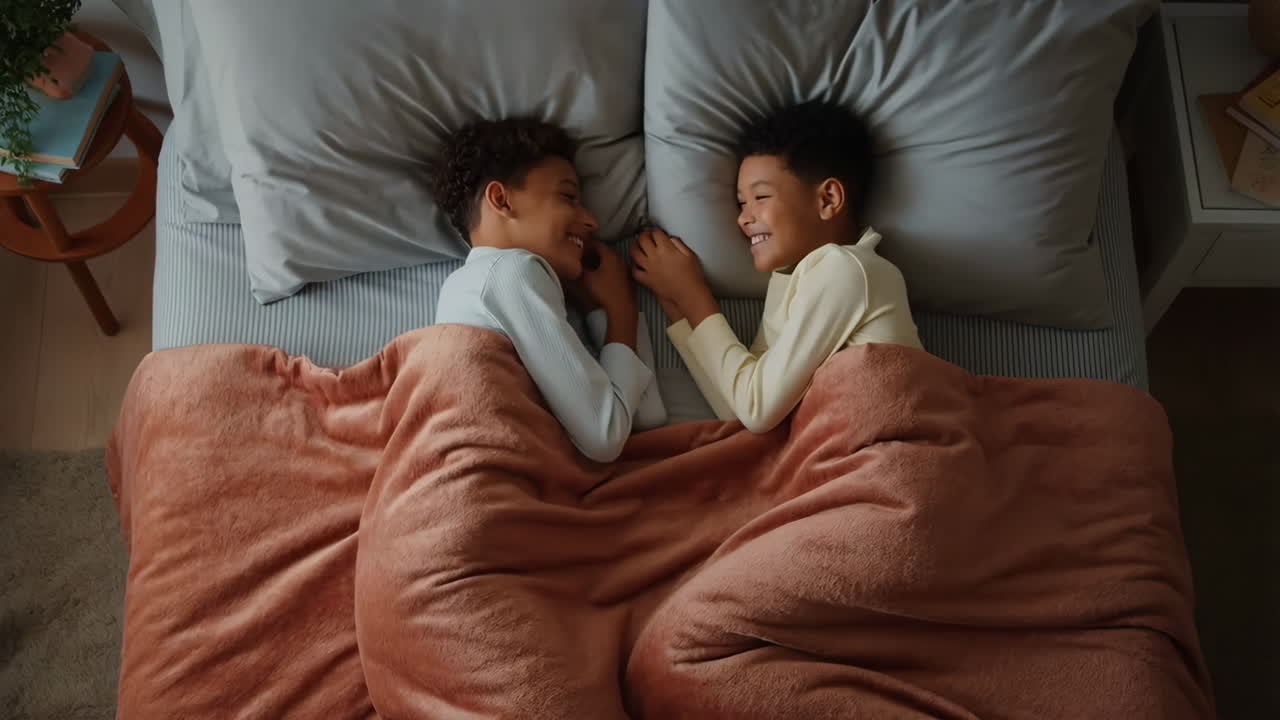 Two young boys smiling and bonding in bed