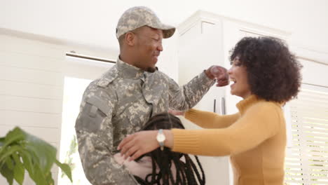 happy african american male soldier embracing his daughter and wife at home, slow motion