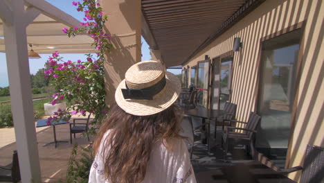 woman in a straw hat walking on a patio of a resort