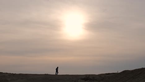 extreme wide shot of a man running across the desert at sunset