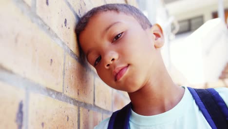 schoolkid leaning on wall in corridor at school