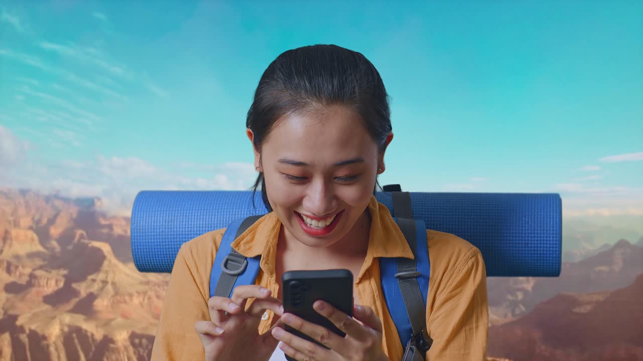 Close Up Of Asian Female Hiker With Mountaineering Backpack Looking At The Smartphone And Saying Wow While Traveling At The Top Of Mountain