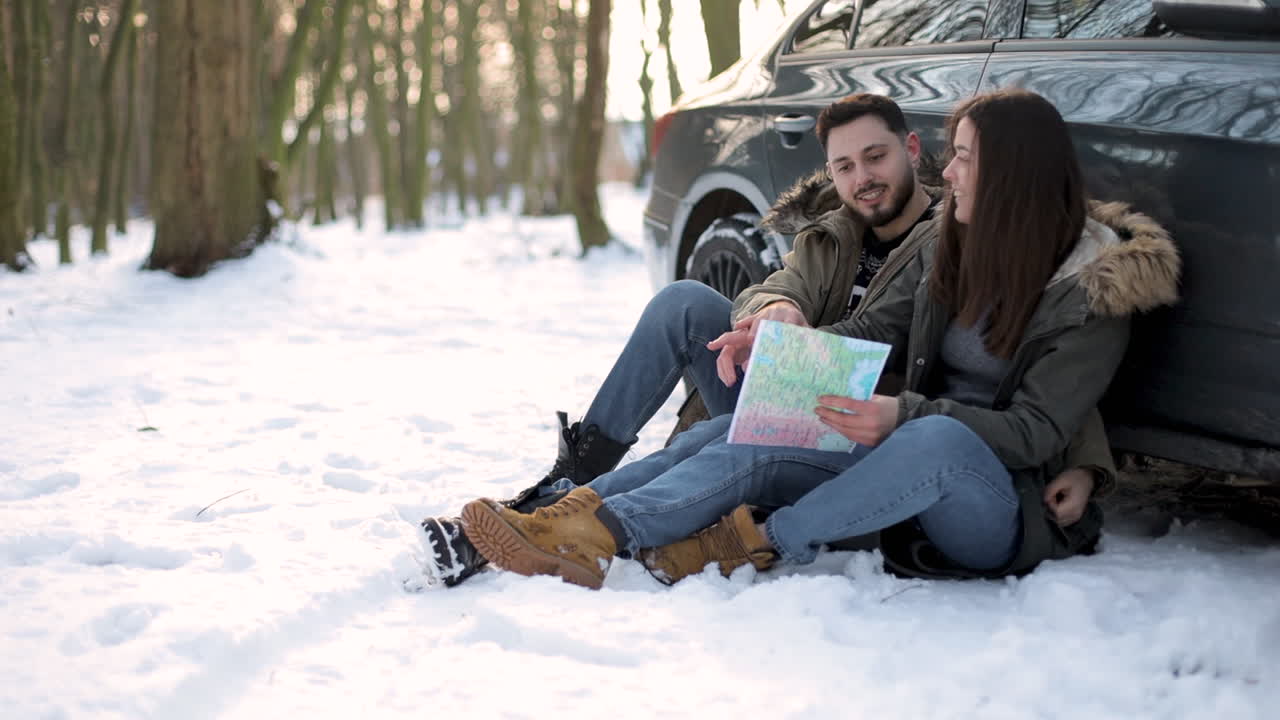 백인 커플은 눈 속에 앉아서 로드트립 동안 쉬고 있다.