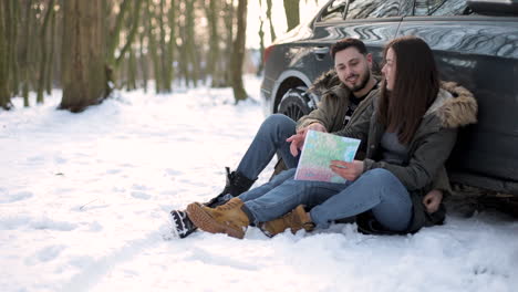 pareja caucásica sentada en la nieve y descansando durante un viaje por carretera.