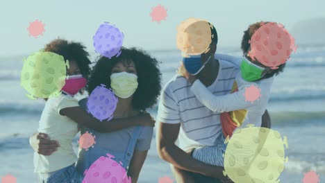 Animación-De-Células-Virales-Sobre-Una-Familia-Afroamericana-Con-Máscaras-Faciales-En-Una-Playa-Soleada