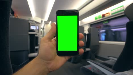 mano sosteniendo un teléfono con una pantalla verde en el tren