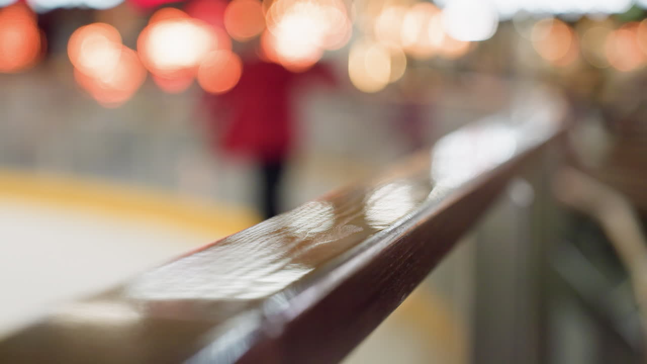 un primer plano de una barandilla pulida con un fondo borroso con una persona con una camisa de manga roja esquiando. este video destaca el movimiento dinámico y la atmósfera vibrante de la zona de esquí