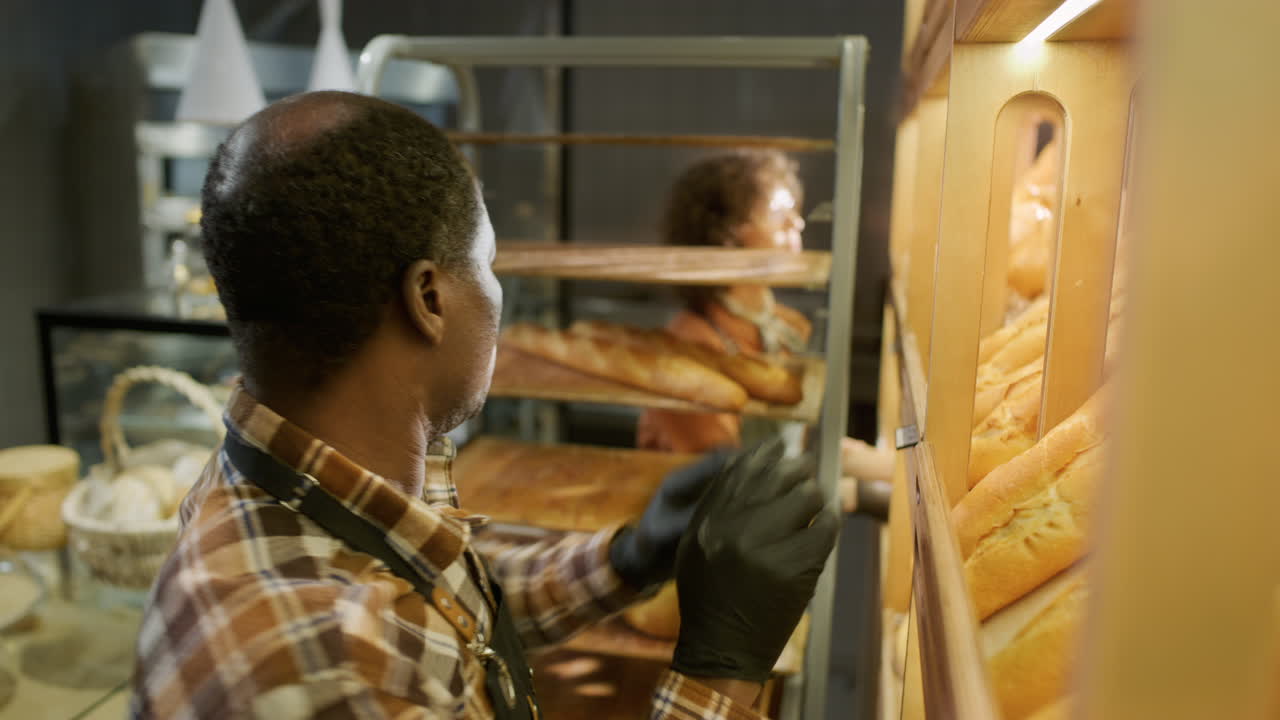 Baker arranging fresh bread in a bakery
