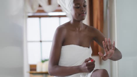 mujer afroamericana atractiva haciendo una manicura en el baño
