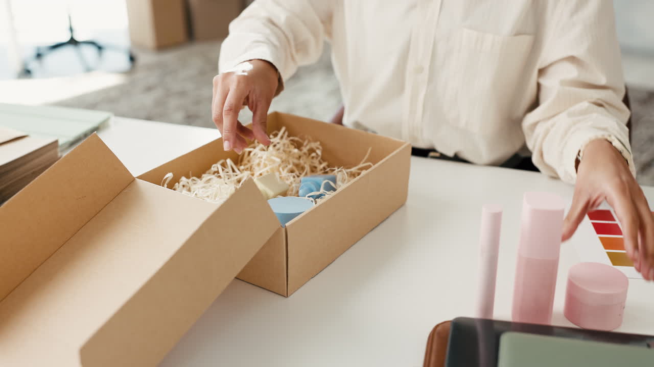 Person's Hands Packing Small Products into a Cardboard Box