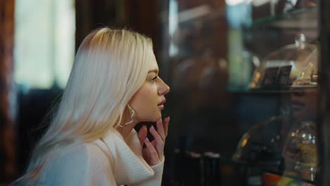 close up of a blonde woman looks at cakes at showcase and makes a choice