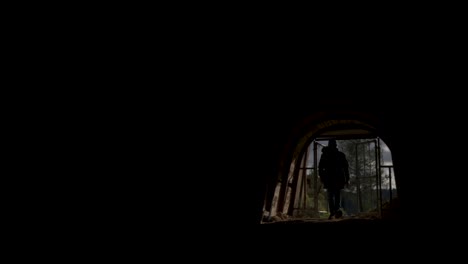 a man opens the gate and walks into a dark tunnel, backlit anonymous footage with copy space