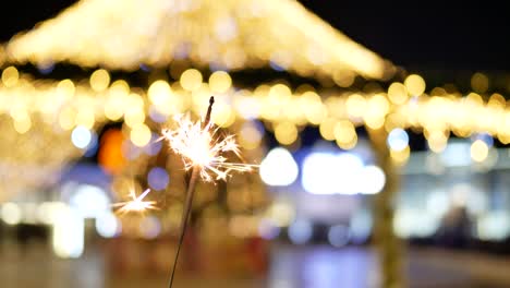 burning sparkler close up in background of the christmas lights on the street