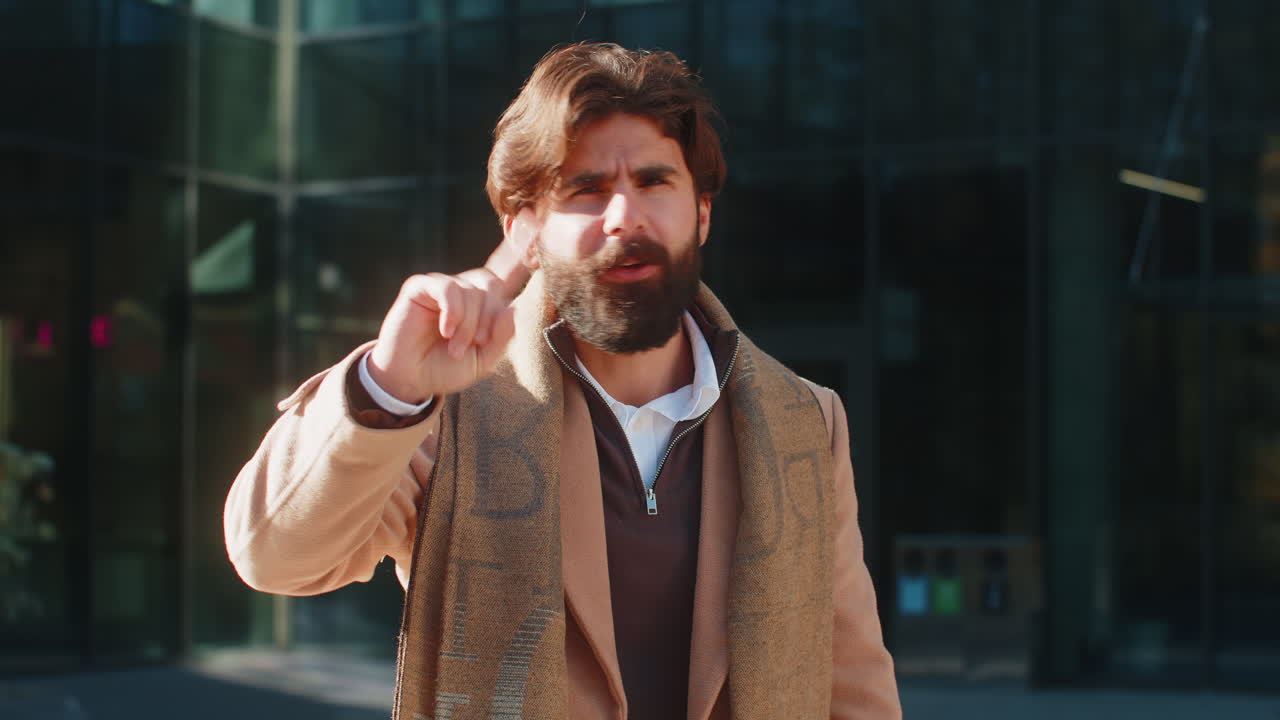 Upset indian man reacting to unpleasant awful idea shaking finger at camera on city urban street