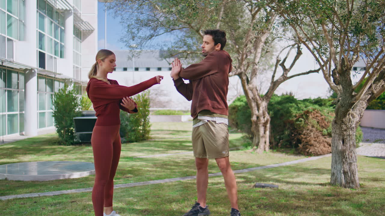 Fitness coach training woman in urban park. Fit sport couple stretching hands