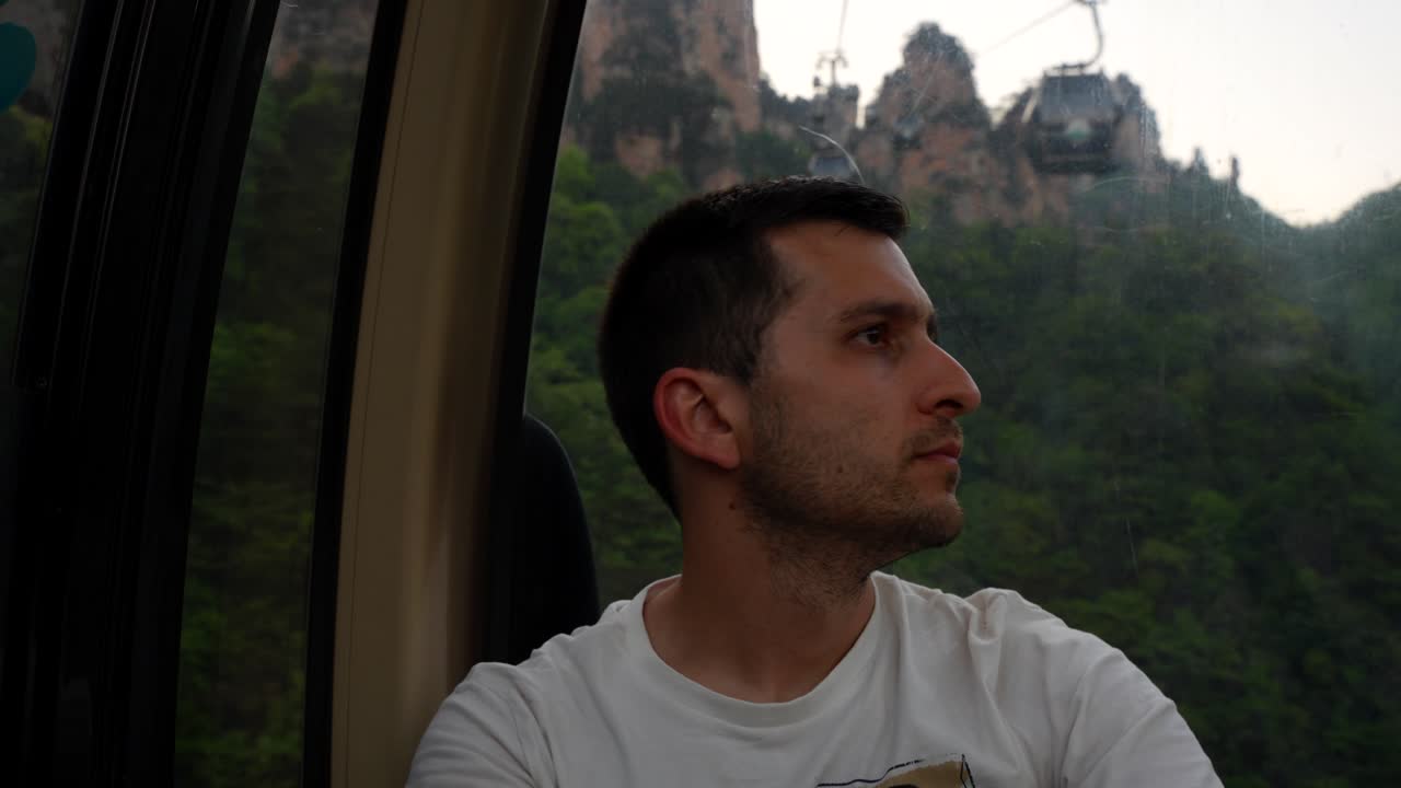 un hombre revisa su cámara mientras viaja en un teleférico sobre la montaña tianzi en zhangjiajie, china