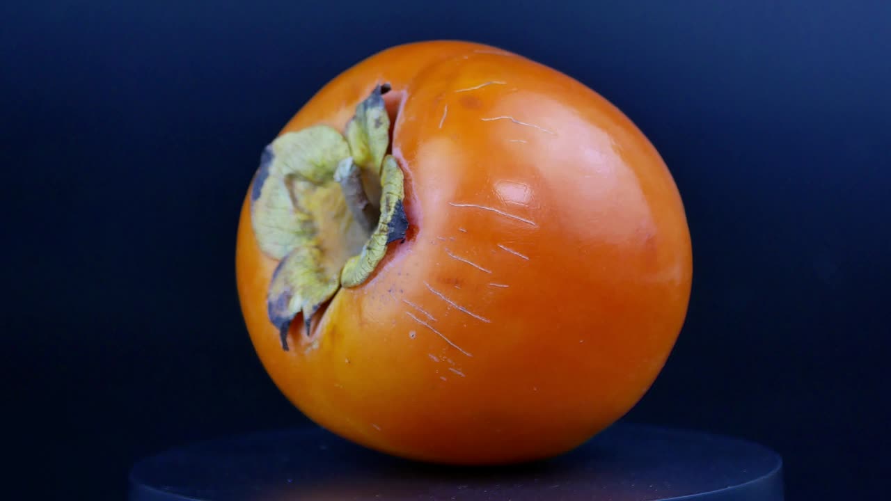 Persimmon spins on a black background. Fruit. Food video. Yes for text.