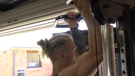 muscly man in home gym exercising chin ups back workout