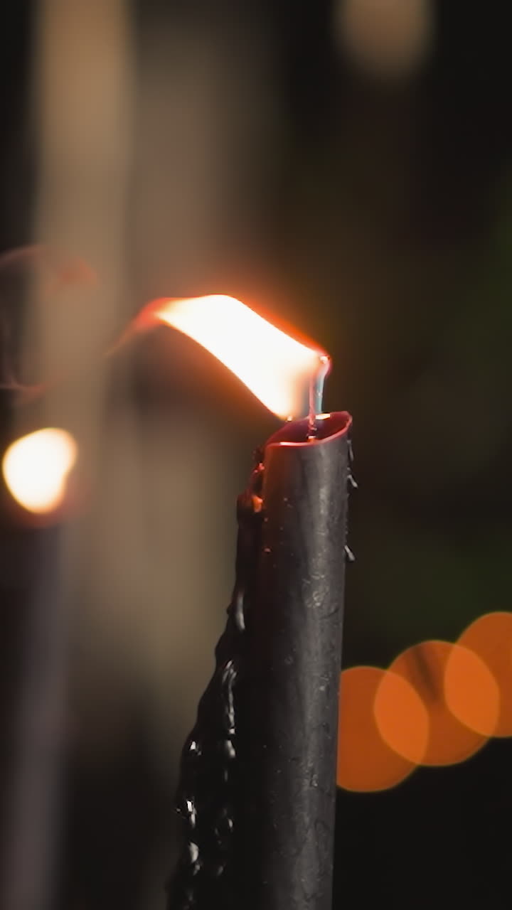 Flickering flame of black candle sways in wind. Stylish candles for romantic dates among nature in evening time closeup. Atmosphere of tranquility