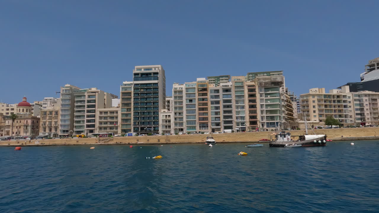 Molo de La Valletta, Malta, dal Mar Mediterraneo, con skyline della città e barche.