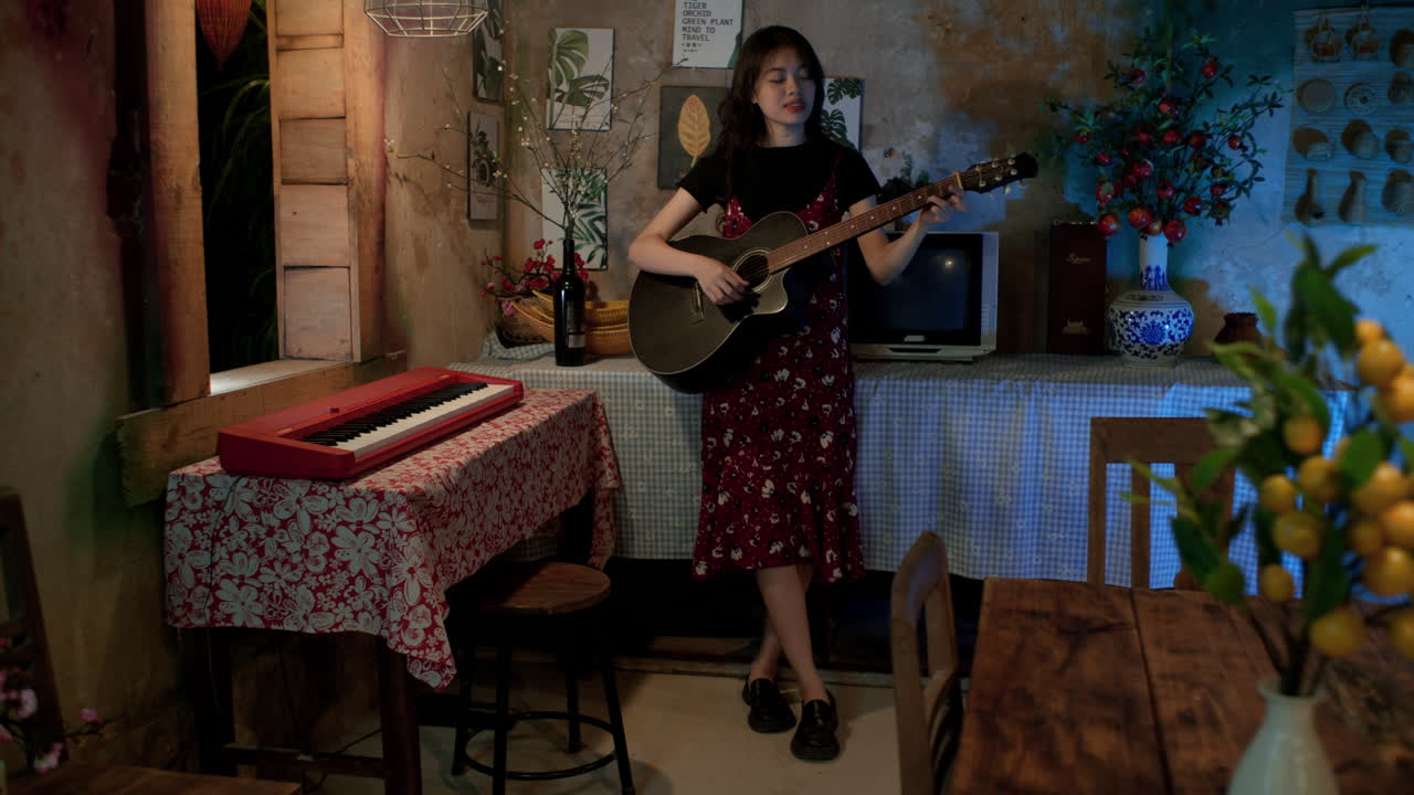 Cute and young Asian woman singing and playing guitar at home, Long shot