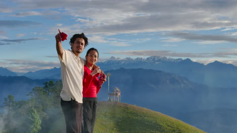 drone shot captures romantic couple drinking tea as clouds pass by, touching them on sailung hill, dolakha, nepal enjoy nature's beauty in mix of sunny and foggy weather with stunning mountain views