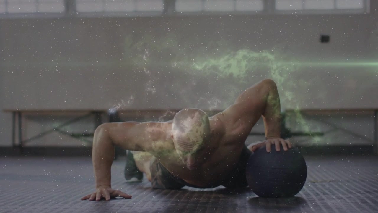 Atleta di fitness che inizia un plank, facendo flessioni con palla medica per la forza, mostrando una sovrapposizione di nebulosa.