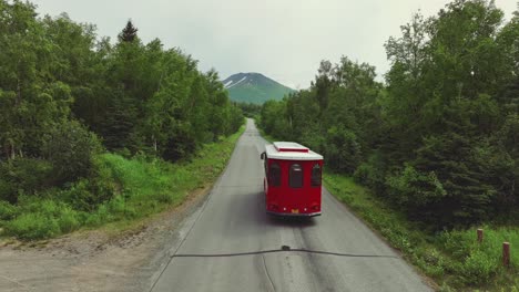 trolley driving through empty road between the forest in anchorage, alaska