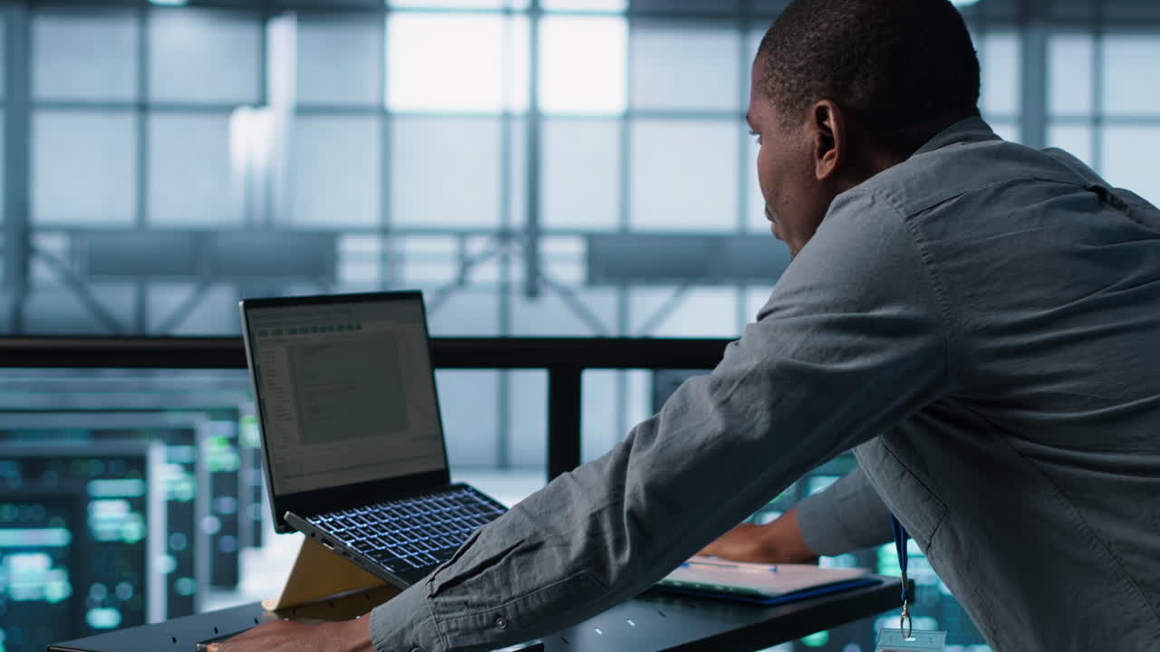técnico codificando en portátil en el centro de datos, administrando la virtualización del servidor