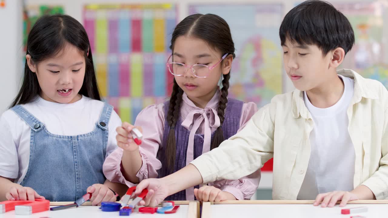 明るい教室で、3人の小学生が色とりどりの磁石で実験している。ミディアムショット、柔らかな照明。